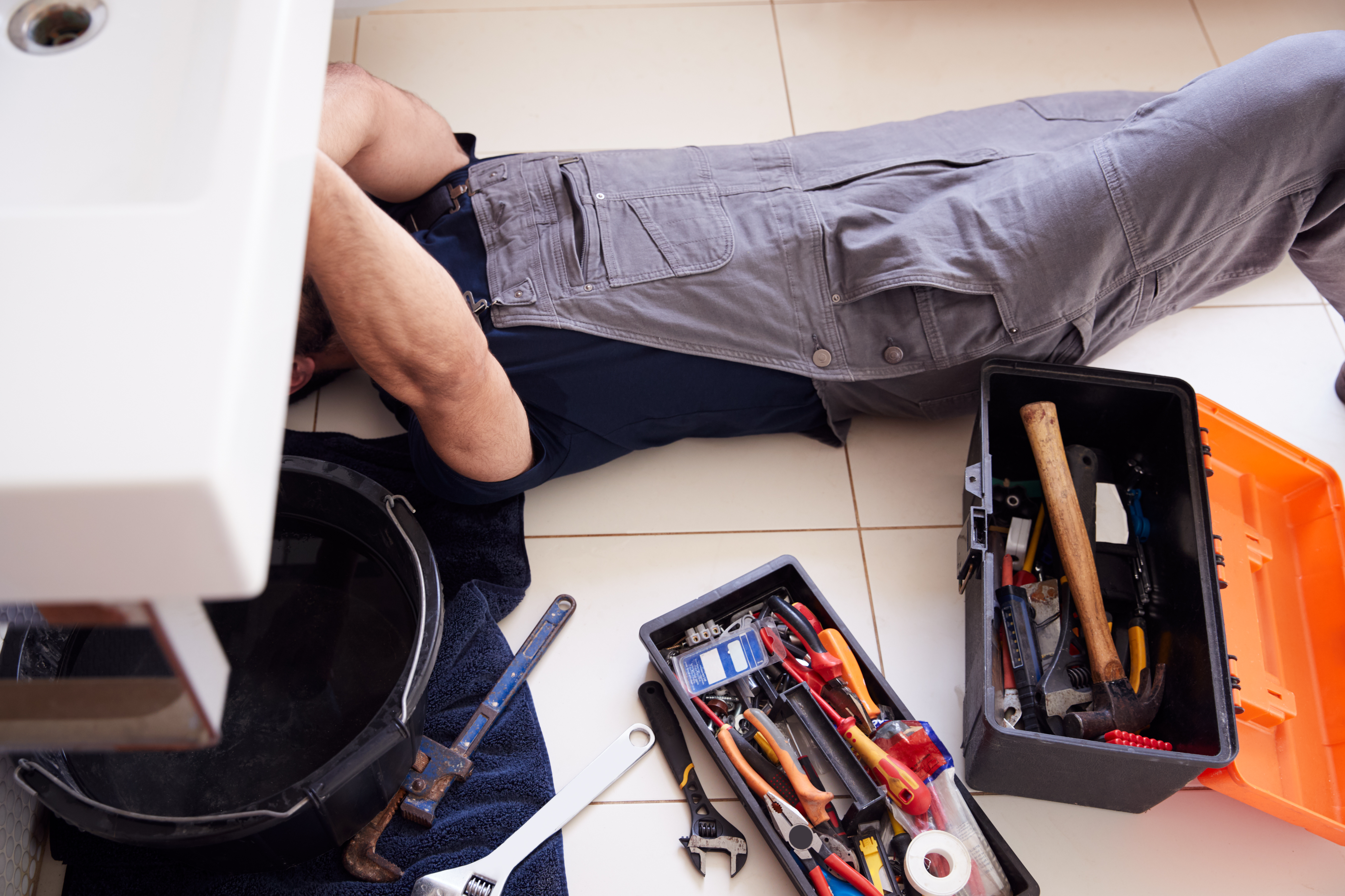 Plombier réparant l'évier avec outils et boîte à outils.
