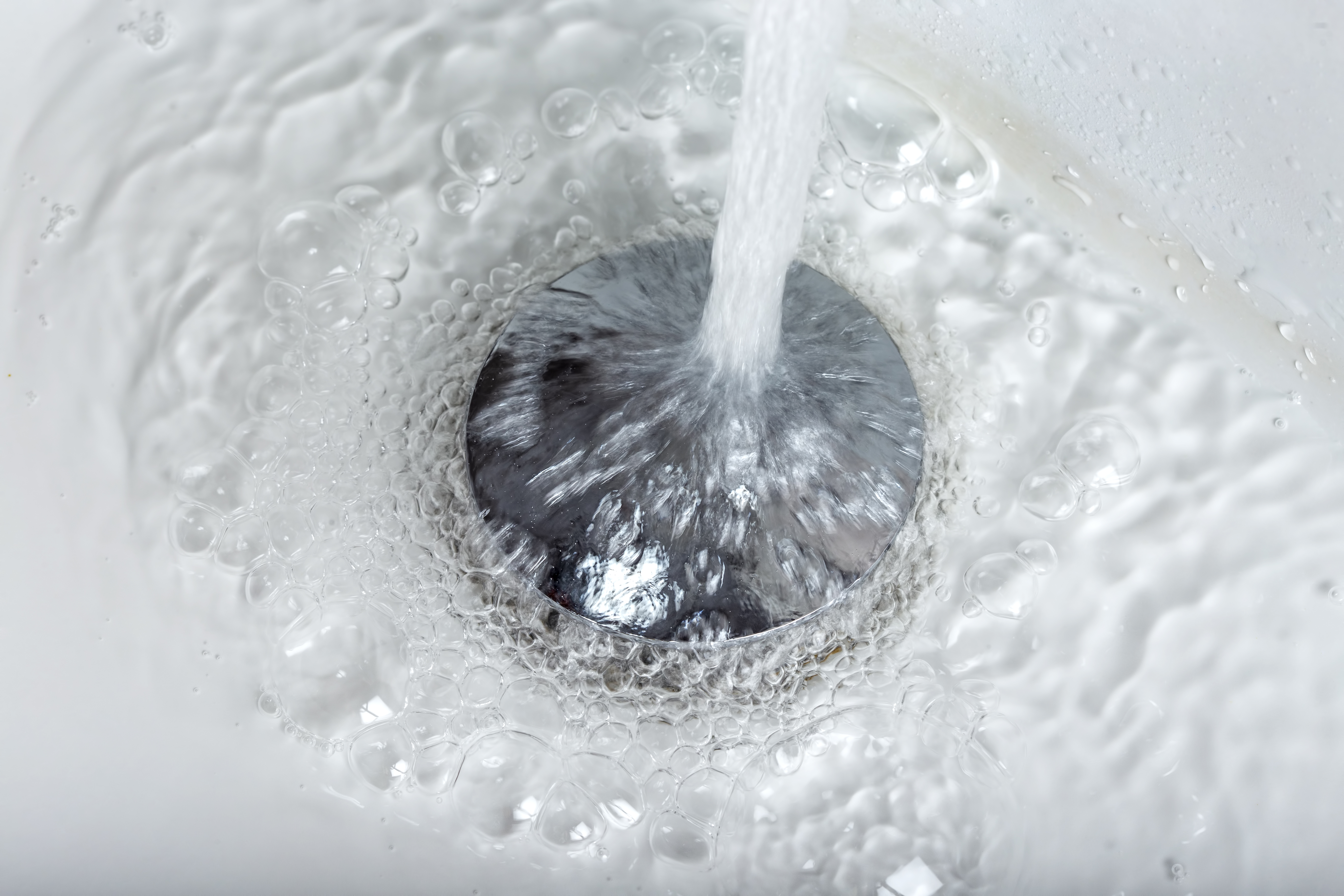 Eau s'écoulant dans un évier avec mousse.